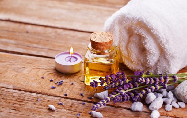 Spa still life with lavender oil, white towel and perfumed candle on natural wood