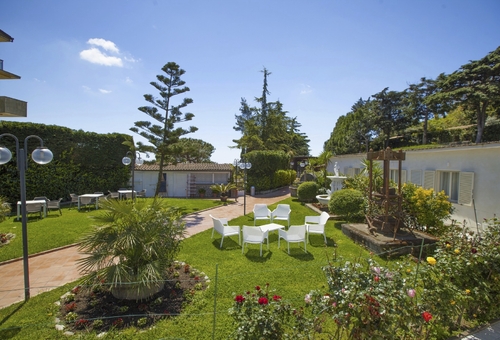 Hotelgarten des O Sole Mio in Sant’Agata sui Due Golfi mit gepflegten Grünflächen, Sitzgelegenheiten und blühenden Beeten vor den Hotelgebäuden